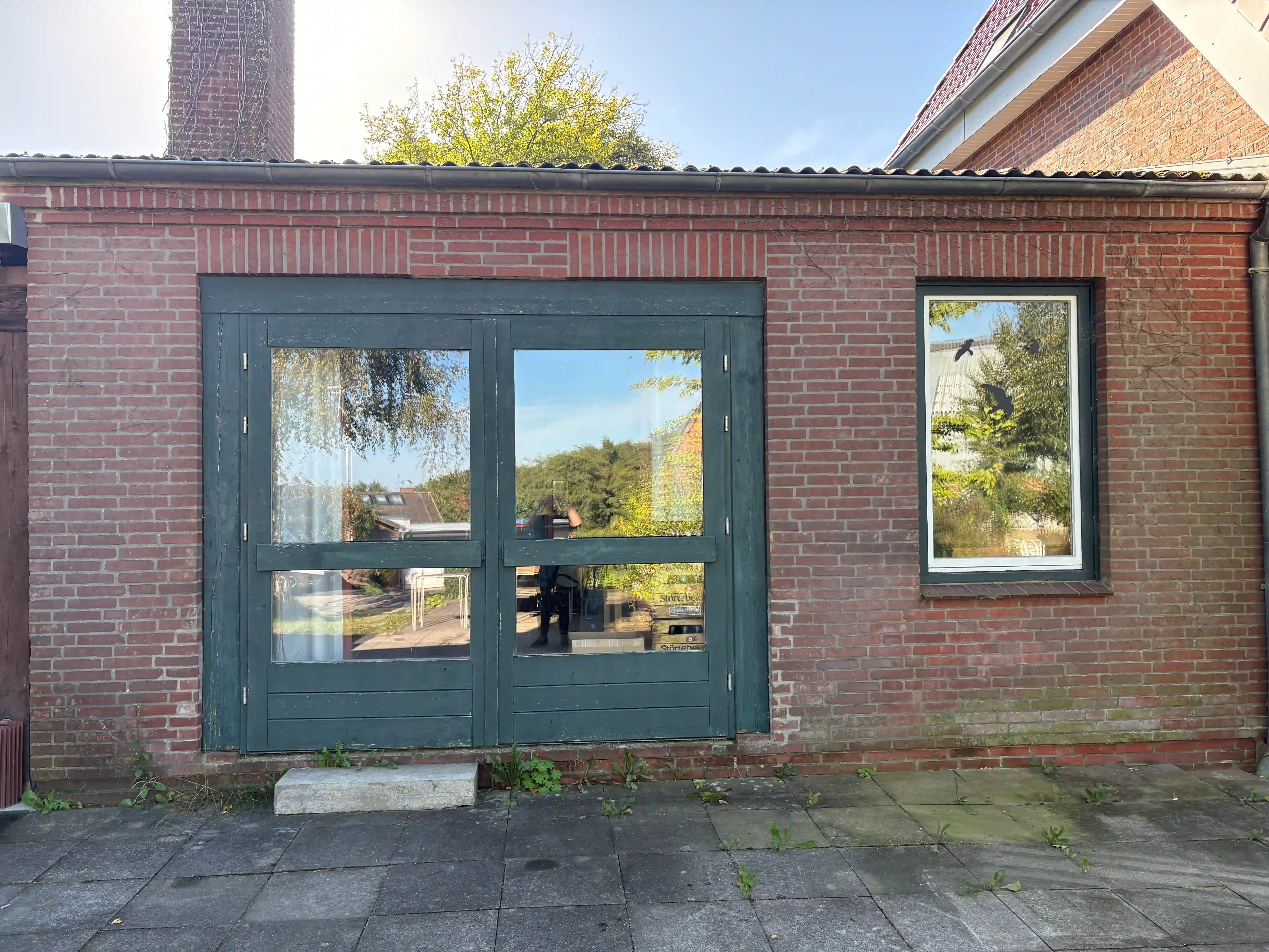Das Atelier von außen: Ziegelbau mit dunkelgrüner Tür an der Wroher Dorfstraße